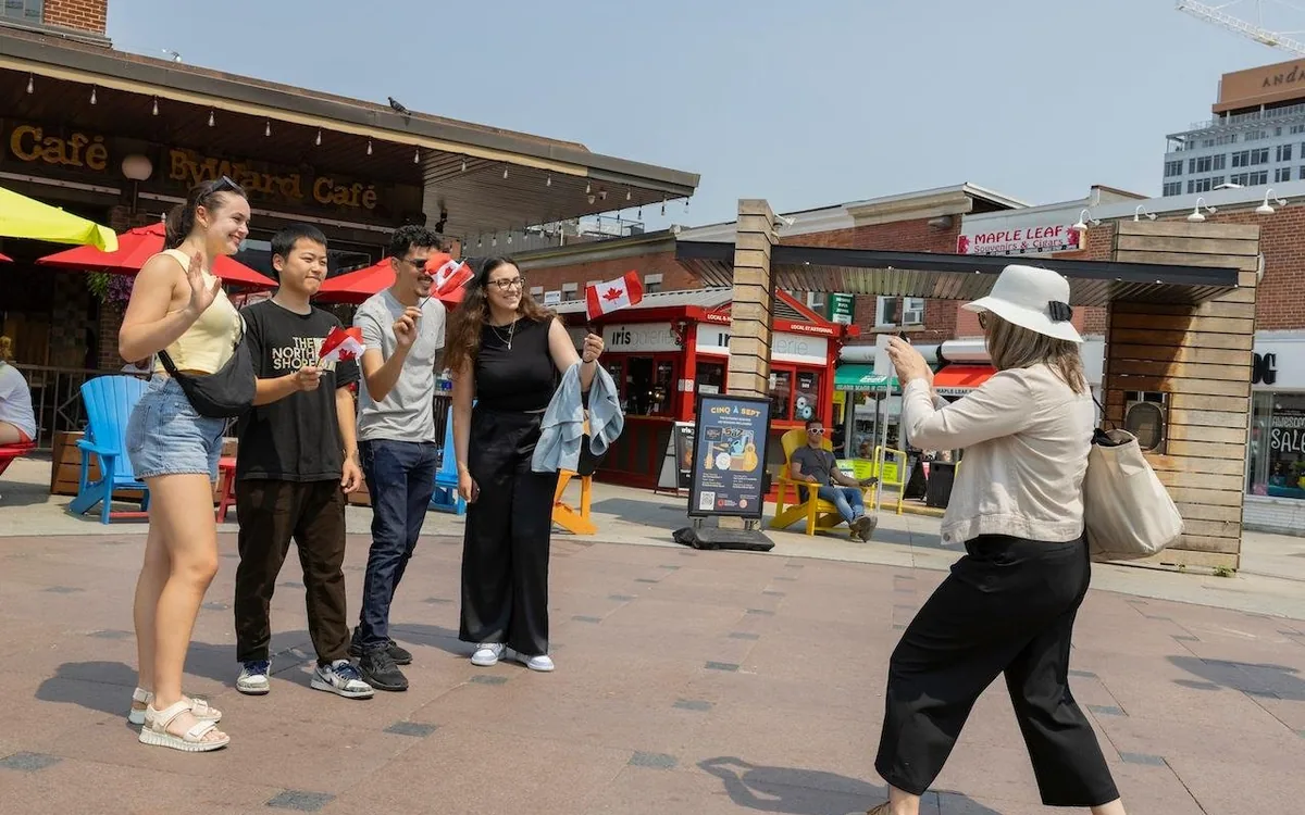 Menschen mit kanadischen Flaggen auf einer sonnigen Straße im ByWard Market