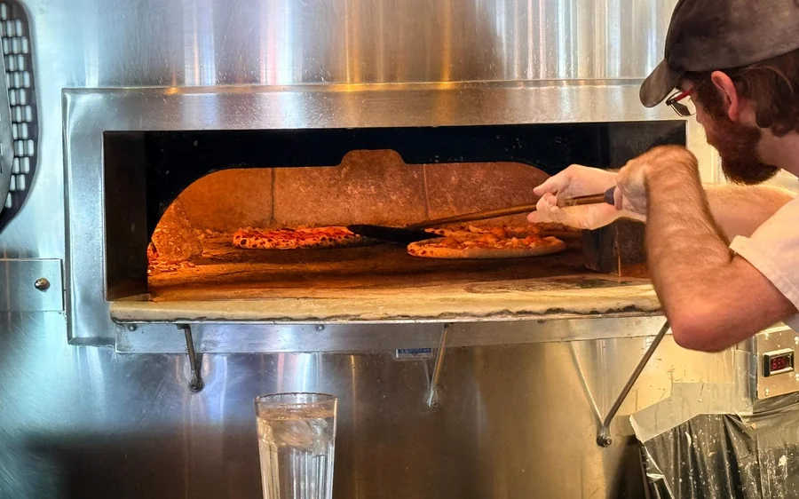 Ein Bäcker holt Fladenbrot aus einem Holzofen